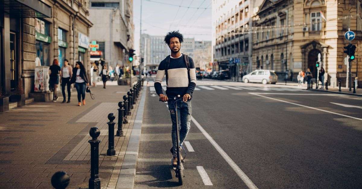 Homme sans casque roulant à trottinette électrique