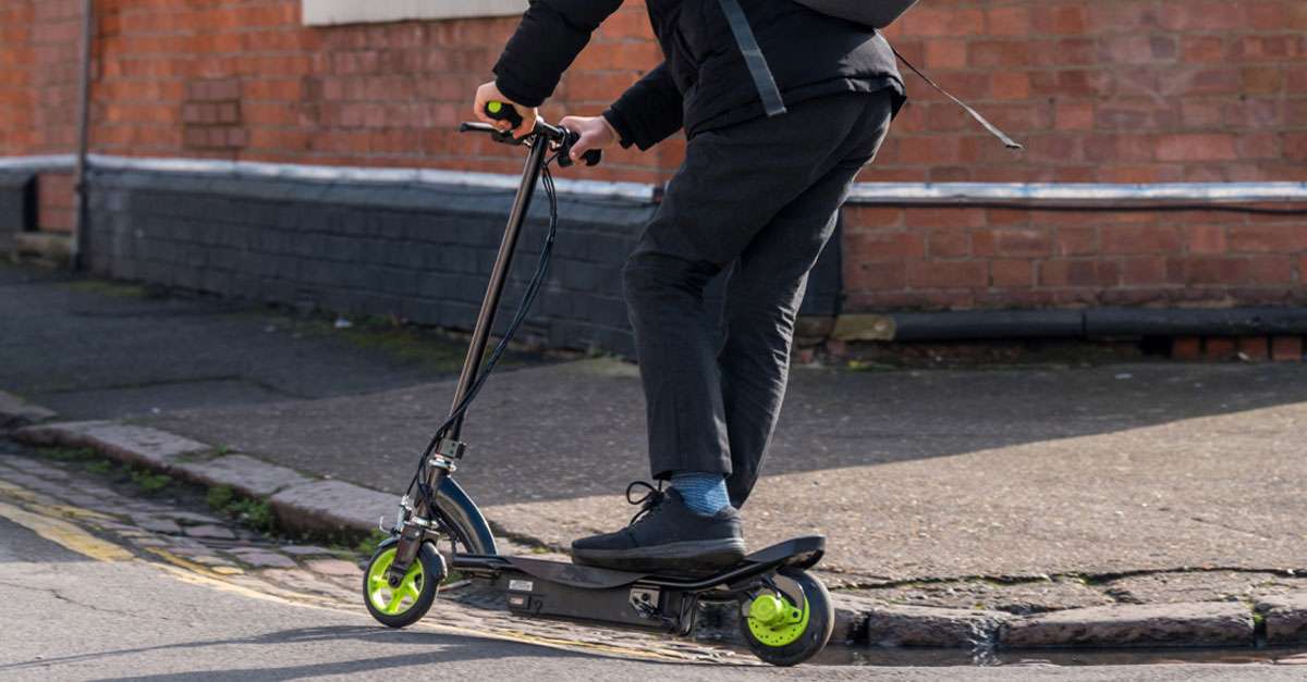 jeune homme à trottinette électrique en milieu urbain