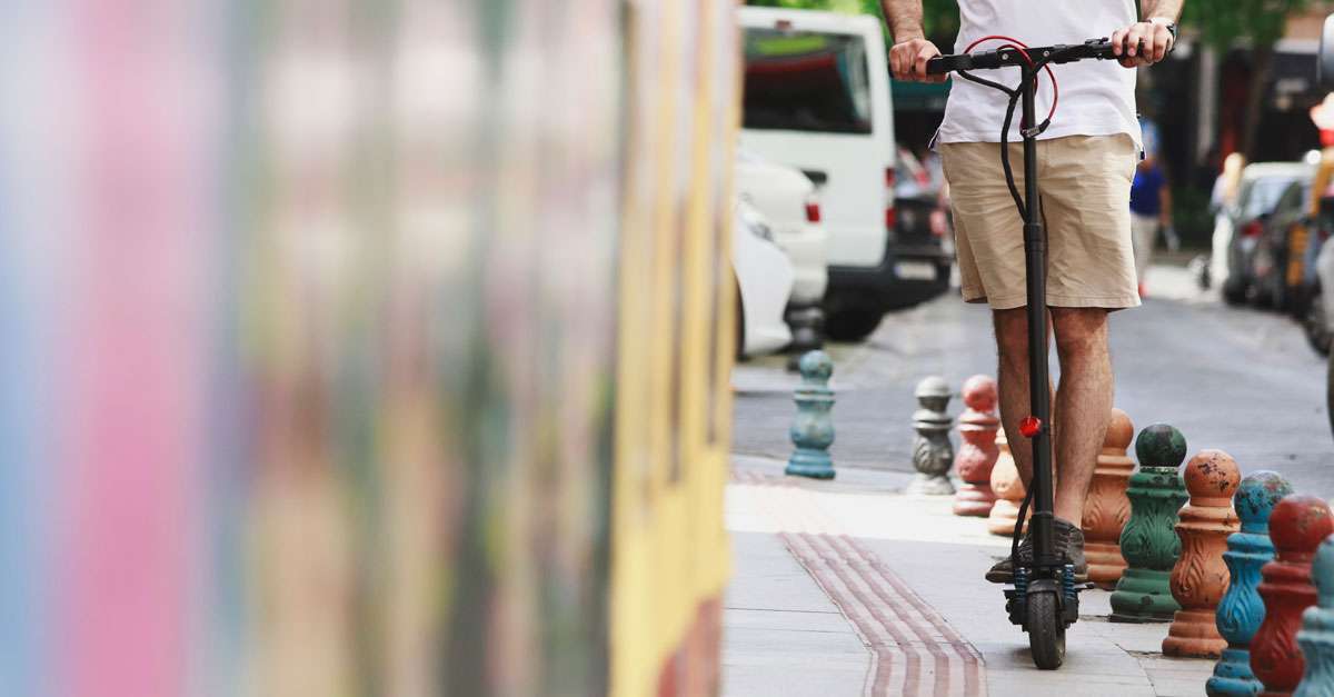 jeune homme à trottinette en ville sur le trottoir