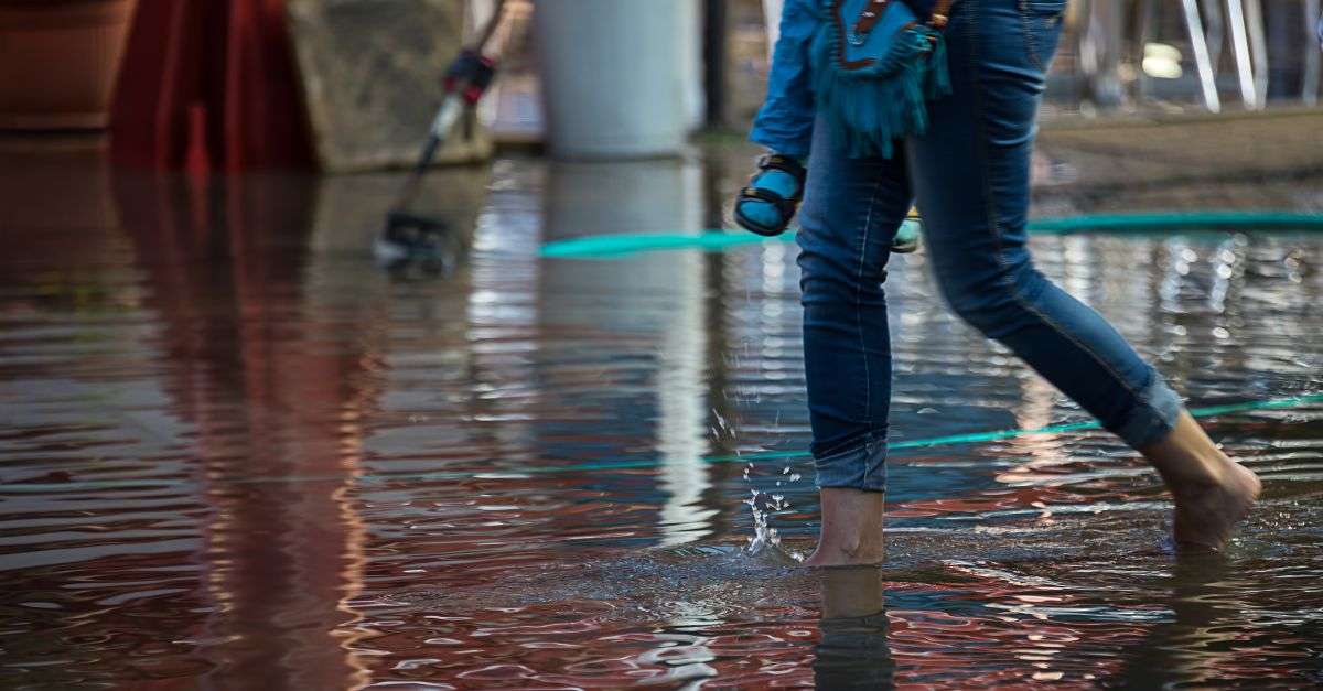 Ville inondée avec une femme qui marchent dans l'eau portant son enfant