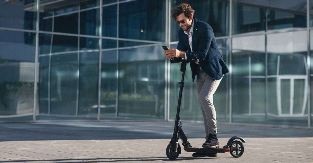 homme sur une trottinette électrique sur son smartphone