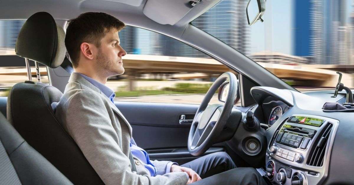 Homme dans une voiture atuonome sans les mains sur le volant mais attentif à la circulation