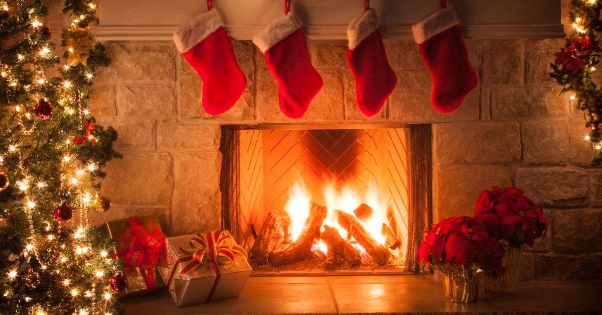 Sapin de Noël décoré avec des boules rouges devant un feu de cheminée 