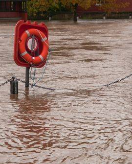 Inondation d’une rivière avec une bouée de sauvetage sur son support au milieu de l’eau débordée