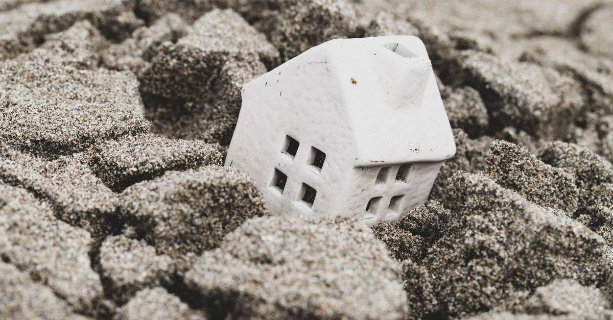 petite maison en céramique enfoncée dans le sable