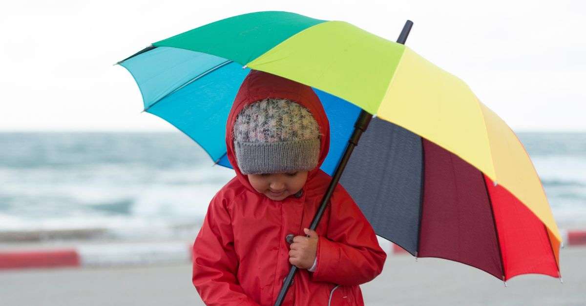 enfant qui porte un parapluie multicolore