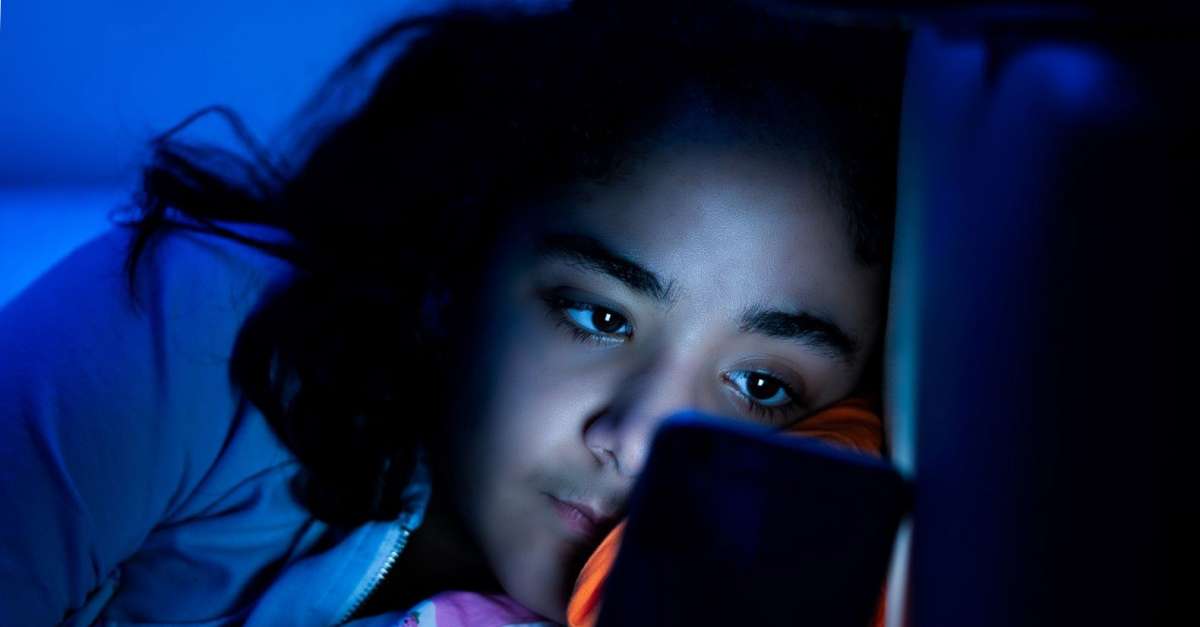 adolescente lisant un smartphone au lit