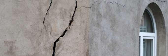 Pignon fissuré sur la façade d'une maison en raison duretraait-gonflement des sols argileux et aux tassements