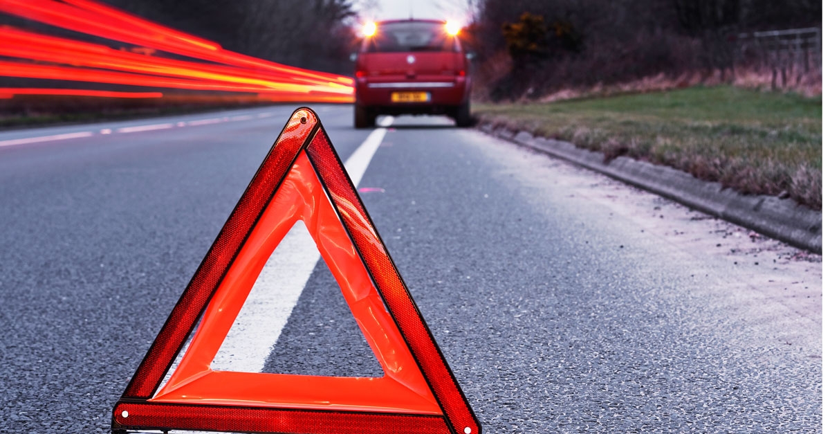 une voiture rouge garée sur le bas-côté avec le triangle  de pré-signalisation placé 30m devant le véhicule