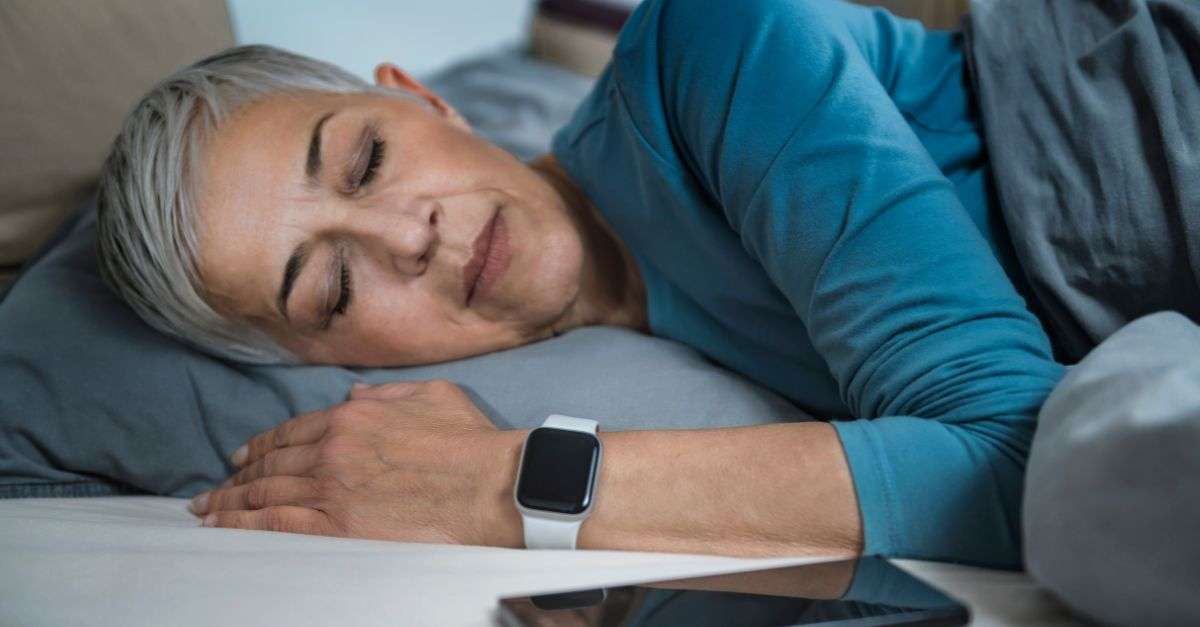 femme qui dort à côté de son smartphone et qui porte une montre connectée