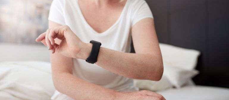 une femme au lit qui consulte son smartwatch