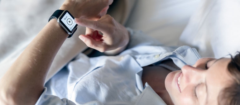 une femme aulit qui consulte son smartwatch