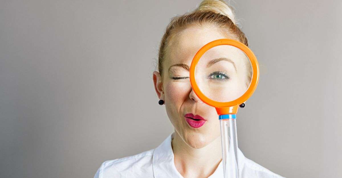 Femme qui regarde à travers une loupe