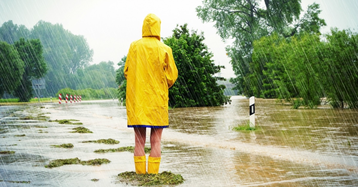 Une personne vue de dos habillée en ciré jaune lors d'une forte pluie et inondations